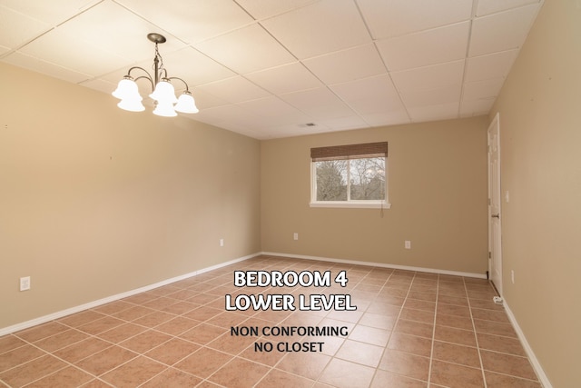 tiled empty room featuring a paneled ceiling and a notable chandelier