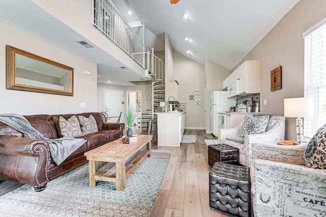 living room with high vaulted ceiling and light wood-type flooring