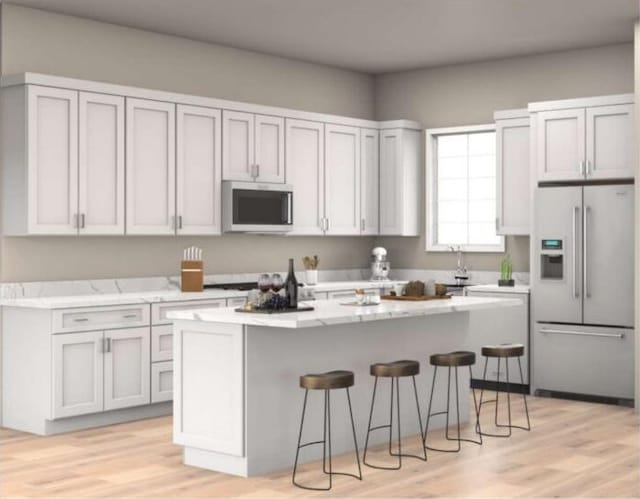 654 Walkington Ln, Branson, MO 65616 - kitchen featuring stainless steel appliances, a kitchen bar, a center island, light wood-type flooring, and light stone countertops