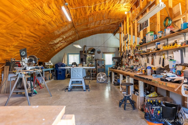 misc room with lofted ceiling, concrete flooring, and a workshop area