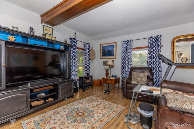 living room featuring wood-type flooring, vaulted ceiling with beams, and a textured ceiling