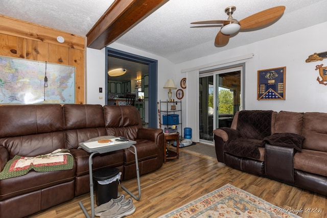 living room featuring hardwood / wood-style flooring, ceiling fan, a textured ceiling, and beamed ceiling