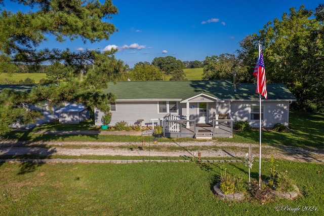 ranch-style house featuring a storage unit, a deck, and a front lawn