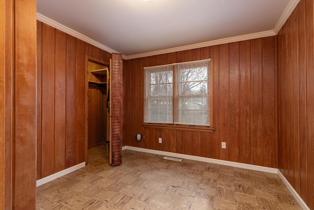 empty room with wooden walls, ornamental molding, and parquet flooring