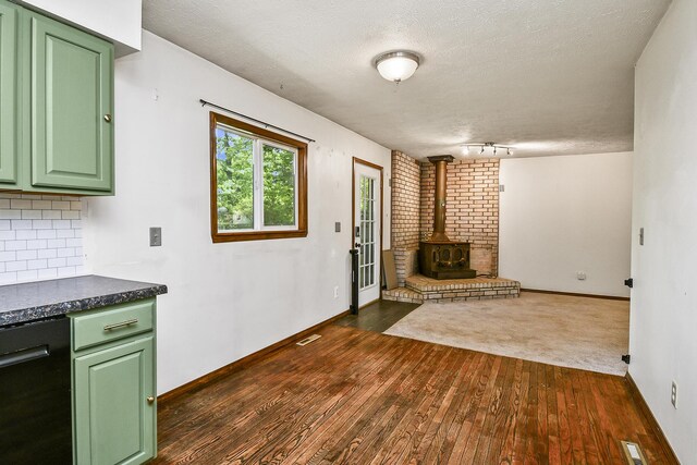 853 E Guinevere St, Springfield, MO 65807 - unfurnished living room featuring a wood stove, dark wood finished floors, a textured ceiling, baseboards, and track lighting