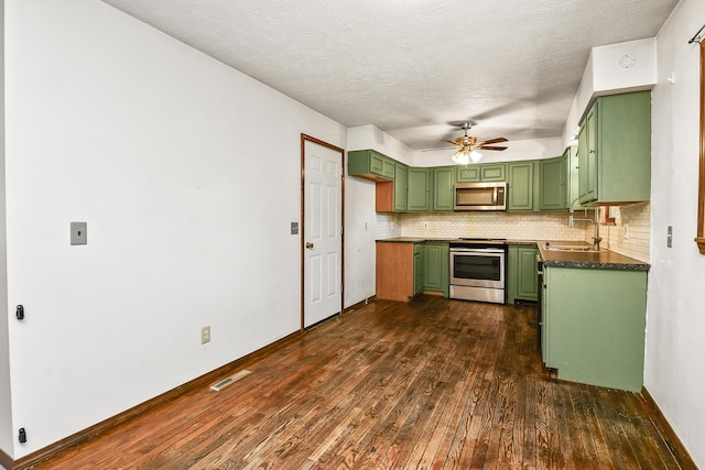 853 E Guinevere St, Springfield, MO 65807 - kitchen with green cabinetry, appliances with stainless steel finishes, a ceiling fan, dark countertops, and dark wood-type flooring