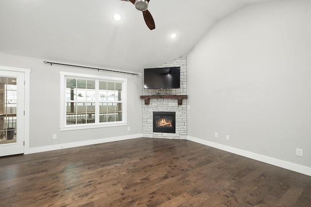 unfurnished living room featuring vaulted ceiling, dark hardwood / wood-style floors, a fireplace, and ceiling fan