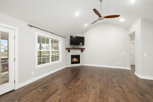 unfurnished living room with a fireplace, vaulted ceiling, dark hardwood / wood-style floors, and a healthy amount of sunlight