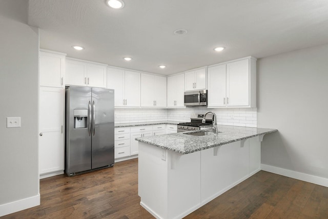 kitchen featuring sink, white cabinetry, light stone counters, appliances with stainless steel finishes, and backsplash