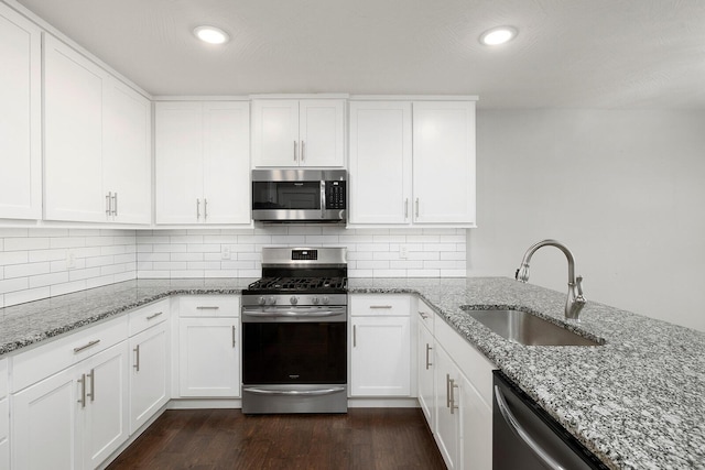 kitchen featuring white cabinetry, stainless steel appliances, light stone countertops, and sink