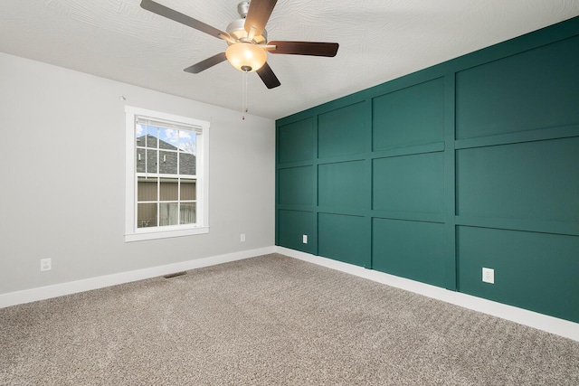 empty room featuring ceiling fan, carpet, and a textured ceiling