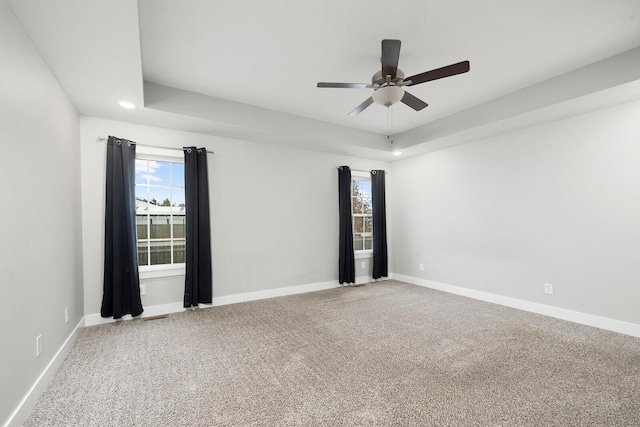 carpeted empty room with ceiling fan and a tray ceiling