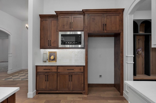 kitchen with built in microwave, wood-type flooring, and tasteful backsplash