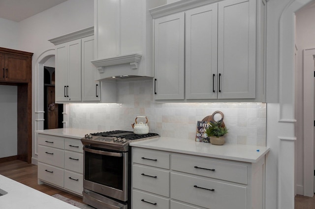 kitchen featuring tasteful backsplash, stainless steel range with gas cooktop, dark hardwood / wood-style floors, and white cabinets