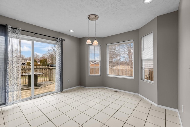 unfurnished dining area featuring a textured ceiling and light tile patterned floors