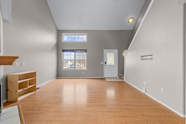 unfurnished living room featuring high vaulted ceiling and light hardwood / wood-style floors