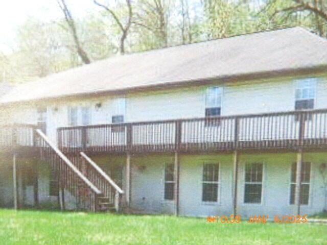 back of property featuring a wooden deck and a lawn