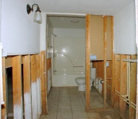 bathroom featuring shower / washtub combination, toilet, and tile patterned floors