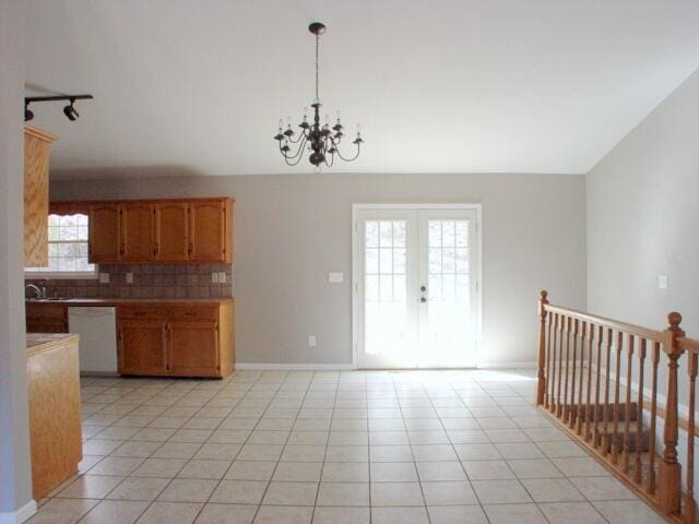 kitchen featuring tasteful backsplash, brown cabinets, decorative light fixtures, white dishwasher, and light countertops