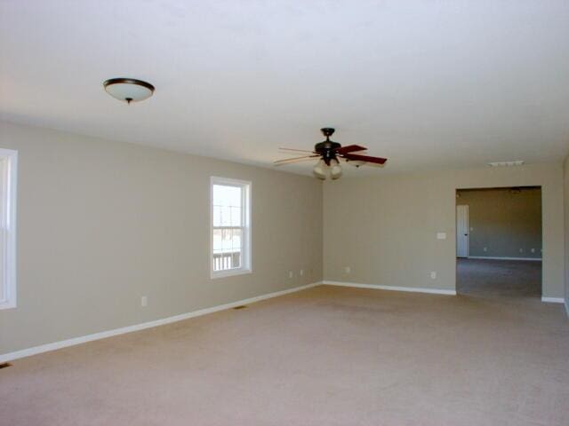 unfurnished room featuring light carpet, baseboards, and a ceiling fan