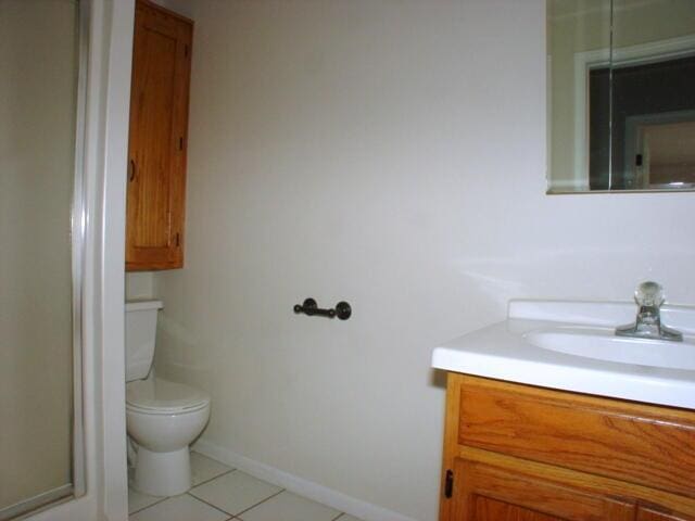 bathroom featuring toilet, tile patterned flooring, baseboards, and vanity