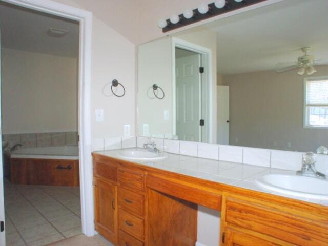 bathroom featuring a ceiling fan, a bathtub, a sink, and double vanity