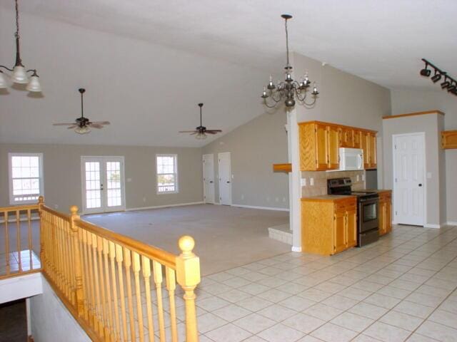 kitchen featuring light tile patterned floors, electric stove, white microwave, open floor plan, and pendant lighting