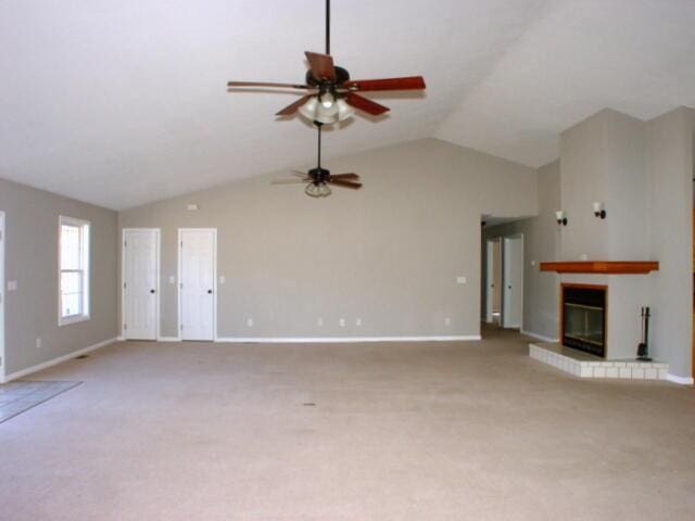 unfurnished living room featuring lofted ceiling, baseboards, light colored carpet, and a glass covered fireplace