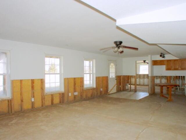 spare room featuring ceiling fan, wainscoting, and wooden walls