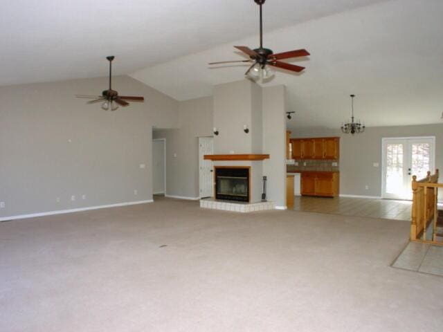 unfurnished living room featuring french doors, a ceiling fan, a glass covered fireplace, carpet flooring, and high vaulted ceiling