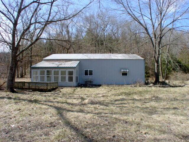 view of front of home featuring a sunroom, metal roof, and a front lawn