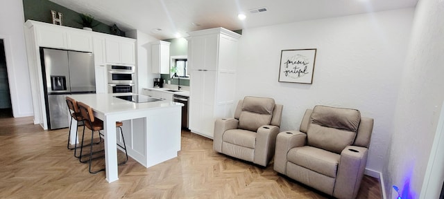 kitchen with a center island, sink, white cabinets, and black appliances