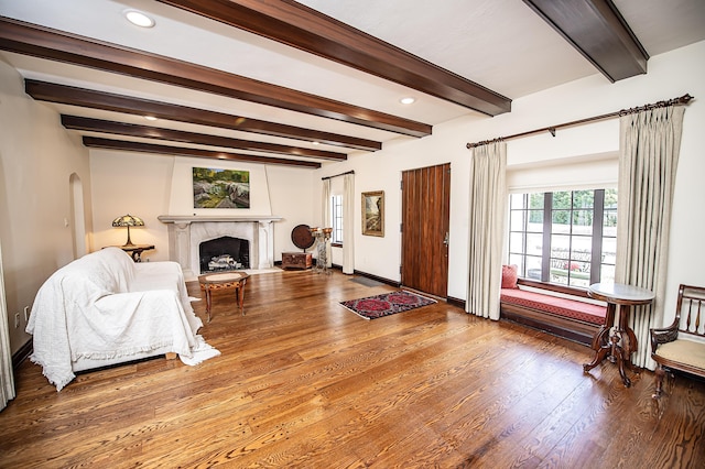 living room with beamed ceiling, wood-type flooring, and a fireplace