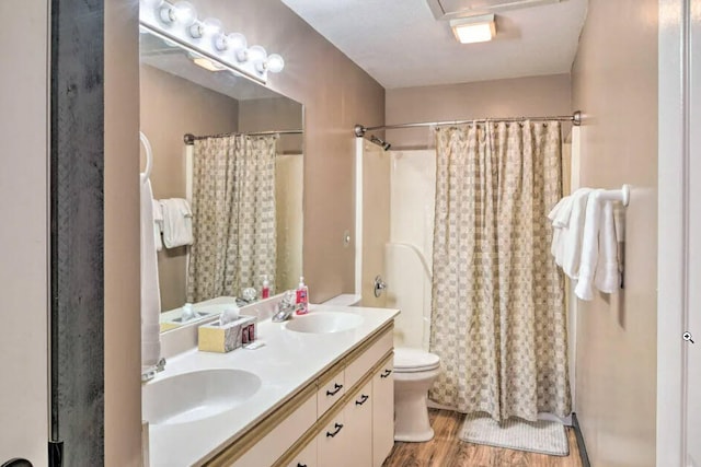 full bath featuring a sink, toilet, wood finished floors, and double vanity