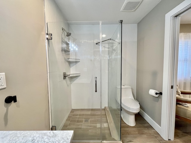 bathroom featuring a shower with shower door and toilet