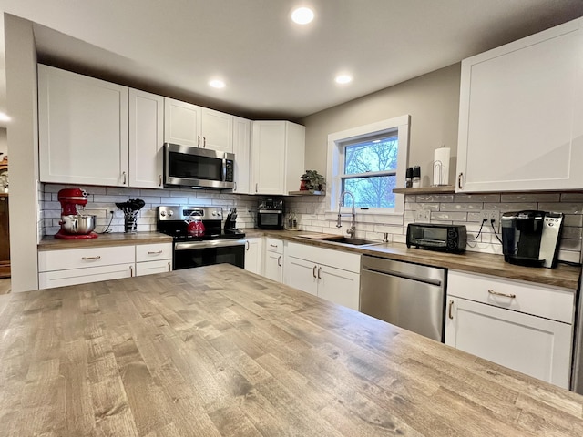 kitchen with white cabinetry, appliances with stainless steel finishes, wooden counters, and sink