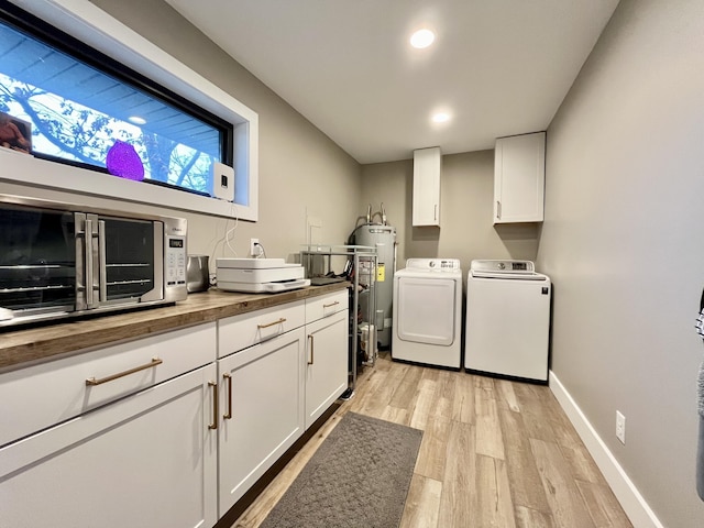 laundry room featuring cabinets, washer and clothes dryer, light hardwood / wood-style floors, and electric water heater