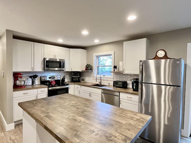 kitchen featuring wood counters, stainless steel appliances, sink, and white cabinets