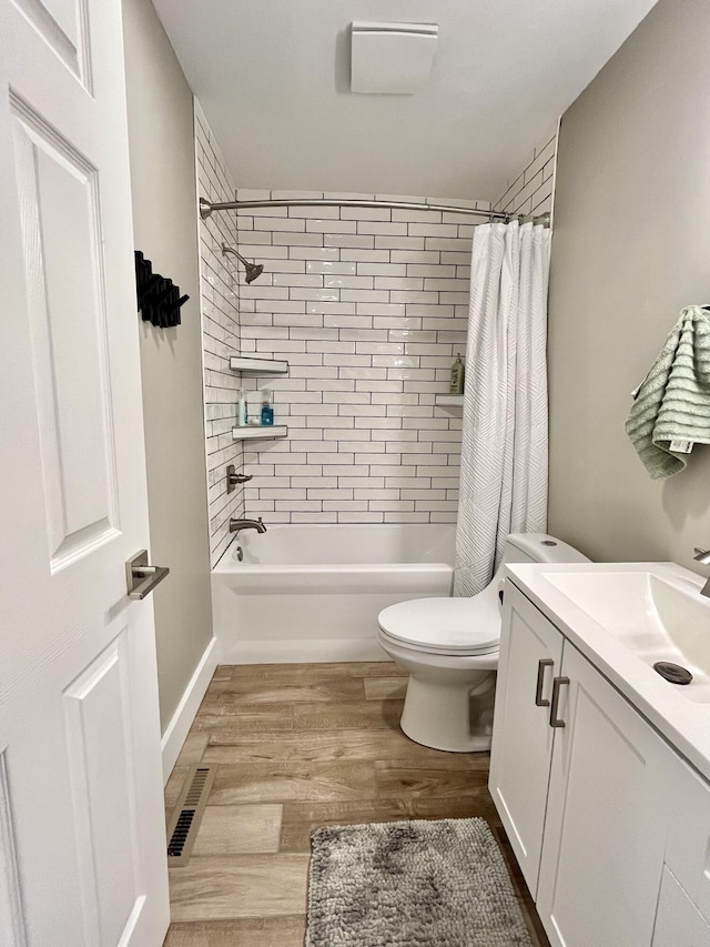 full bathroom featuring vanity, hardwood / wood-style flooring, shower / bath combination with curtain, and toilet