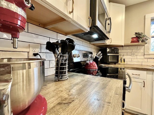 kitchen with wood counters, white cabinetry, stainless steel appliances, and decorative backsplash