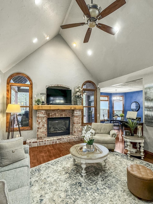 living room featuring vaulted ceiling, a brick fireplace, hardwood / wood-style floors, and ceiling fan