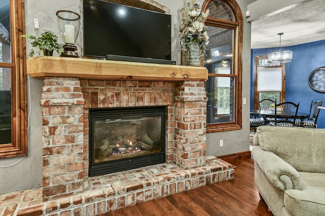 details featuring hardwood / wood-style flooring, an inviting chandelier, a brick fireplace, and a textured ceiling