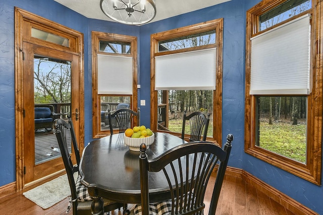 dining room with hardwood / wood-style flooring, plenty of natural light, and an inviting chandelier