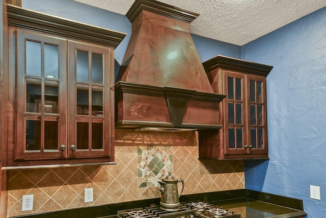 kitchen with decorative backsplash, custom exhaust hood, and a textured ceiling