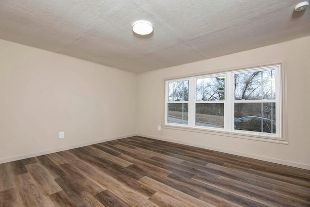 spare room with dark hardwood / wood-style floors and a textured ceiling