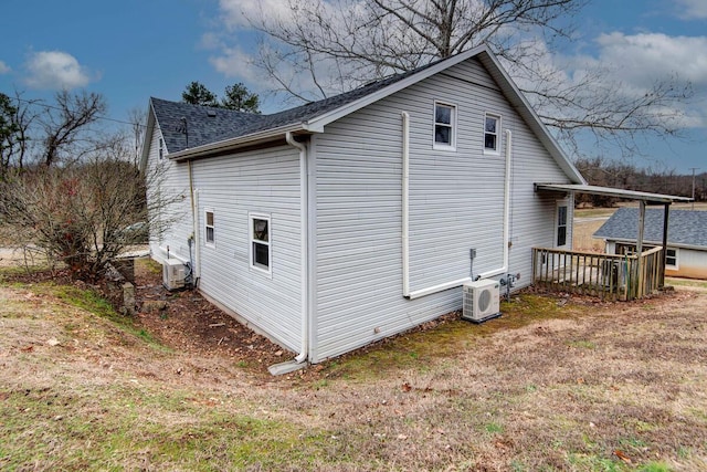 view of side of property featuring ac unit, a lawn, and a deck