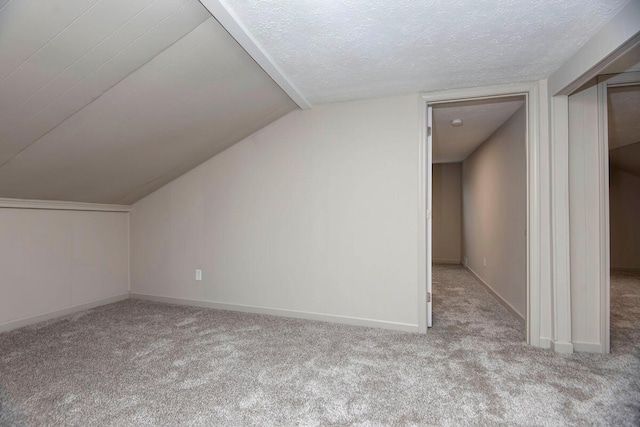 bonus room with light colored carpet, vaulted ceiling, and a textured ceiling