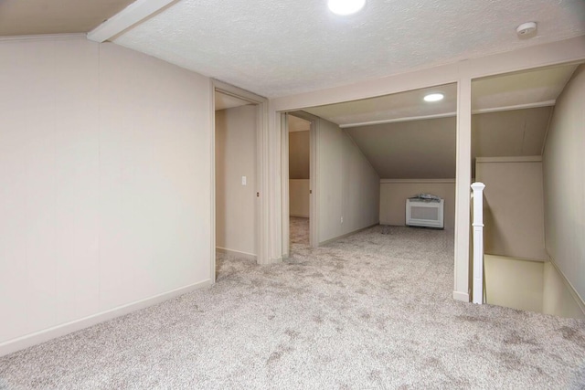 additional living space featuring light carpet, lofted ceiling with beams, and a textured ceiling