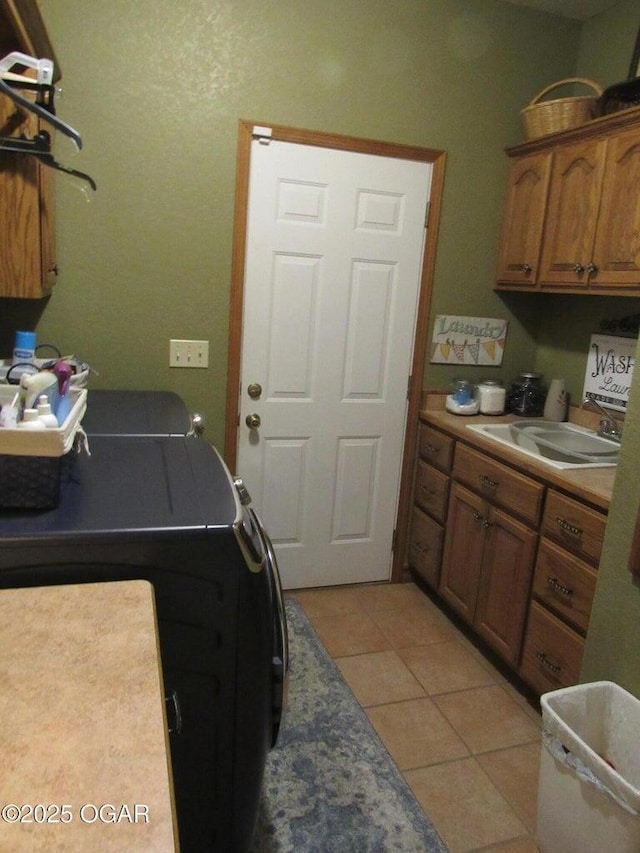 clothes washing area with cabinets, sink, washing machine and dryer, and light tile patterned floors