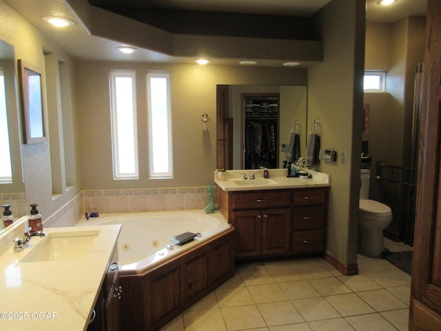 bathroom with tile patterned flooring, vanity, a tub, and toilet